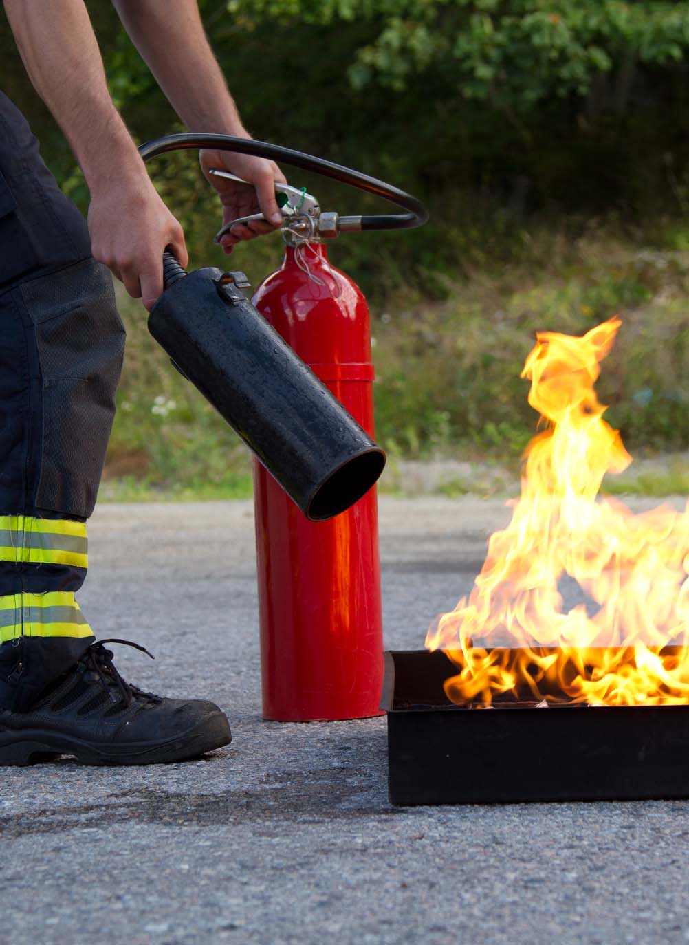 Fire training. Instructor showing how to use a fire extinguisher on a training fire